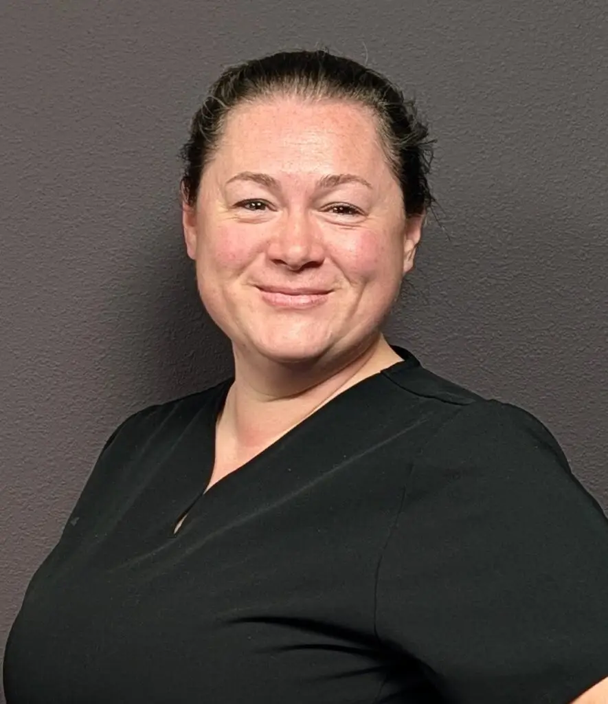 Headshot of a Female nurse with brown hair in a black scrub top
